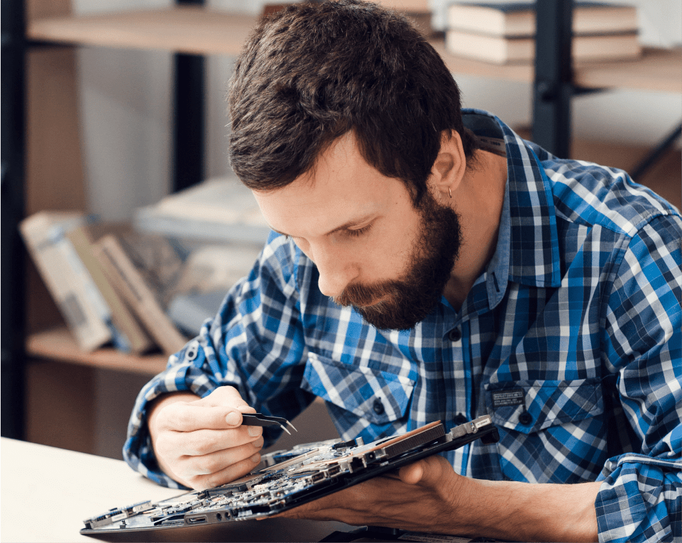 Man inspecting computer motherboard with tool.