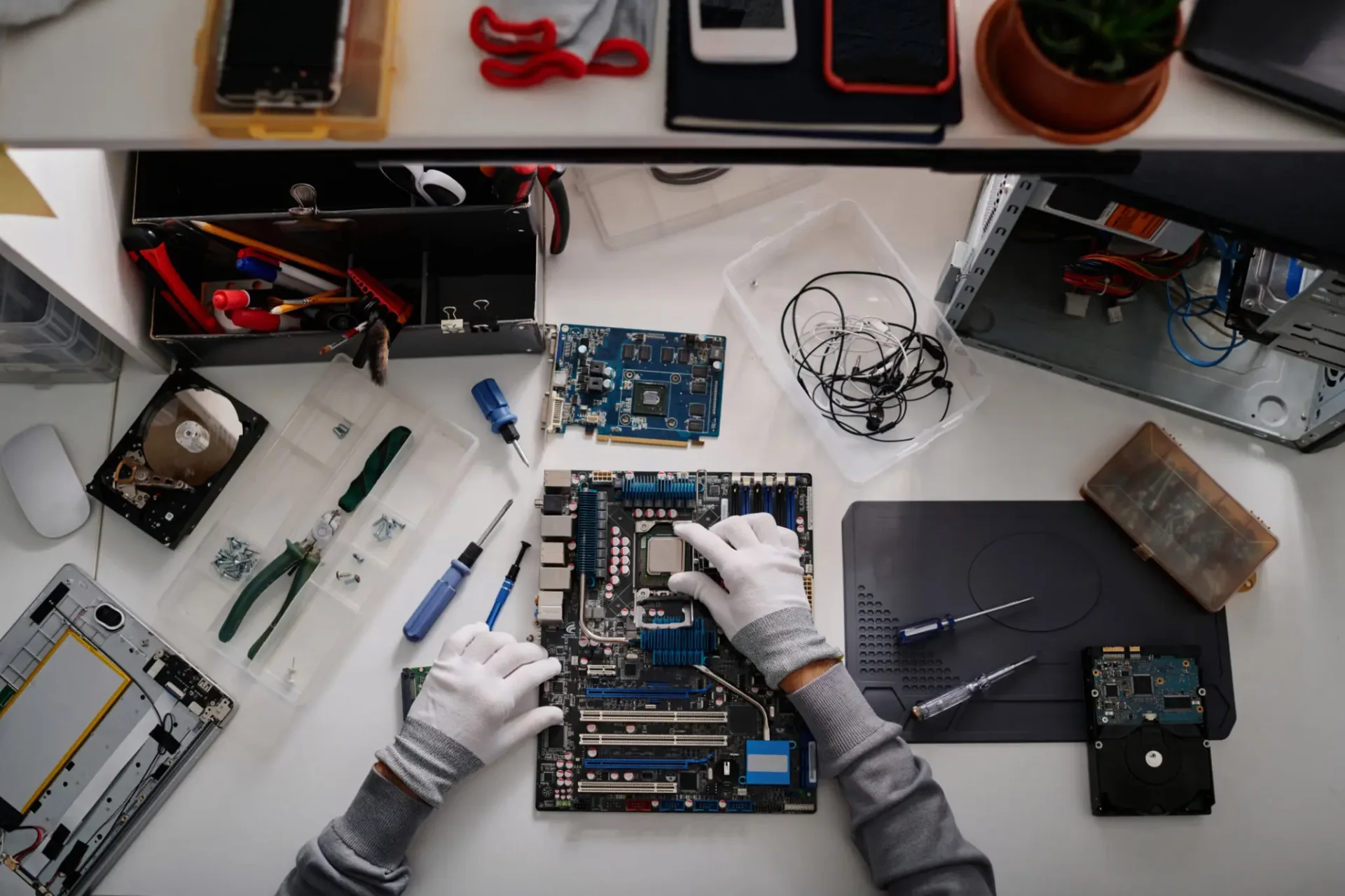 A technician repairing a computer motherboard with tools on the side.