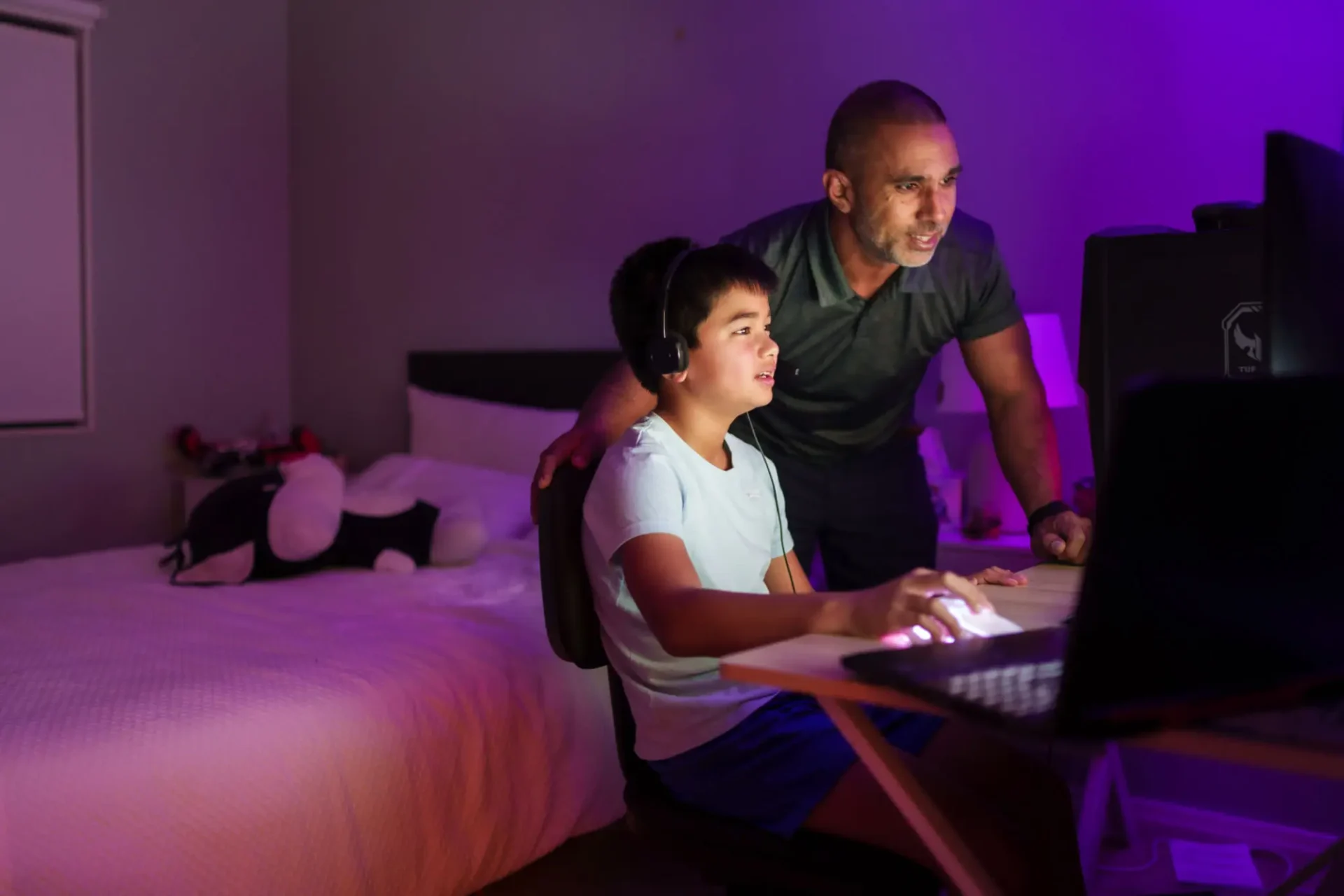 Father and son enjoying gaming together at night.