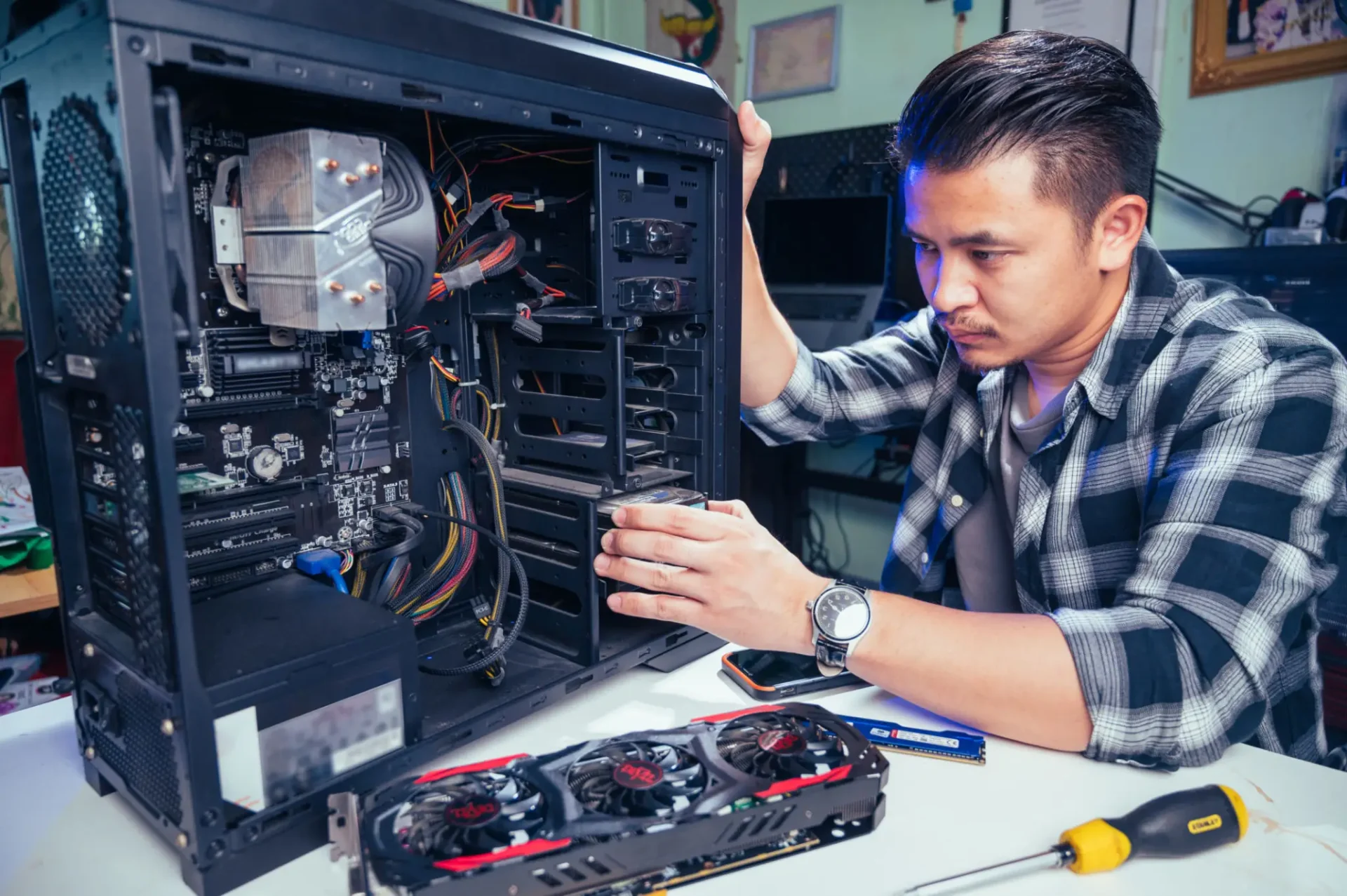 Technician repairing a desktop computer with tools.
